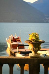 a vase with flowers sitting on a railing next to a boat at Ortensie & Oleandri al Lago - by MyHomeInComo in Argegno