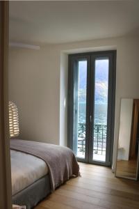 a bedroom with a bed and a view of the ocean at Ortensie & Oleandri al Lago - by MyHomeInComo in Argegno