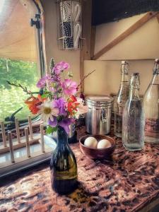 uma mesa com um vaso com flores e garrafas em Truck & Pod creative nature retreat. em Bantry