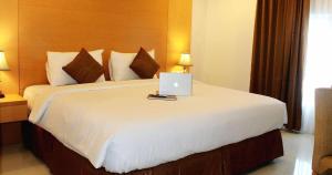 a bedroom with a bed with a laptop on it at Grand Asia Hotel in Makassar