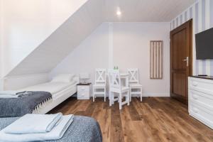 a white room with two beds and a table at Willa Green in Kąty Rybackie