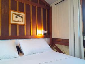 a bedroom with a white bed with a wooden headboard at Recanto das Bromélias Chalés in Guarda do Embaú