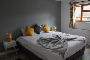 um quarto com uma cama com almofadas amarelas e cinzentas em Hardwick House em Banbury