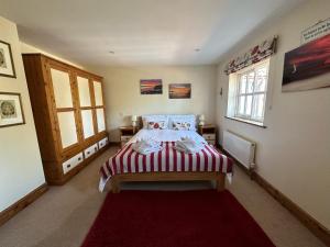 a bedroom with a bed with a red rug at Rockhopper Cottage, Waldringfield in Woodbridge