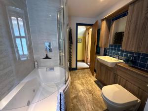 a bathroom with a tub and a toilet and a sink at Rockhopper Cottage, Waldringfield in Woodbridge
