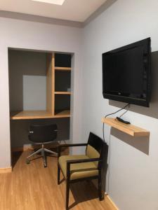 a living room with a tv and a chair and a desk at Spencer Residencial APARTAMENTOS in Praia