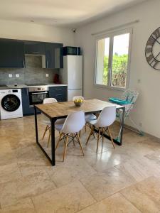 a kitchen with a wooden table and white chairs at Appartement à 200m des plages. in Fréjus