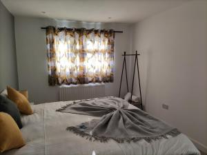 a bed with a blanket on it with a window at Hardwick House in Banbury