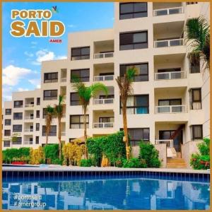 un edificio con palmeras frente a una piscina en Porto said بورتوسعيد غرفتين وصاله, en Puerto Saíd
