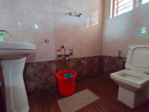 a bathroom with a sink and a toilet and a bucket at Snowdrop inn coorg in Madikeri