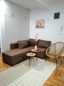 MB apartman في Obrenovac: غرفة معيشة مع أريكة بنية وطاولة