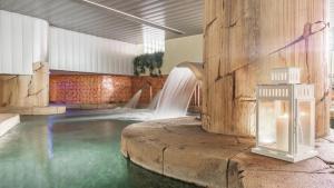 a swimming pool with a waterfall in a building at Playa Home Helgueras con acceso a Spa (AguaMarinaSpa) in Noja