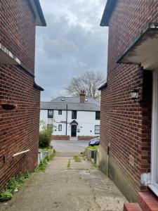 an alley between two brick buildings with a white building at Wembley Homes Serviced Apartment, 25mins to Central London in Wembley