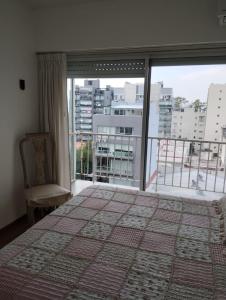 a bedroom with a large window and a bed and a chair at Departamento Zona Puerto De Olivos in Olivos