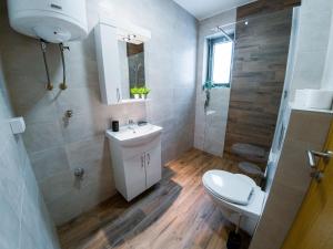 La salle de bains est pourvue de toilettes blanches et d'un lavabo. dans l'établissement Apartman Bellini 2, à Sokobanja