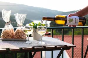 una persona vertiendo vino blanco en dos copas sobre una mesa en Regouro - an Hidden Gem in Douro Valley 