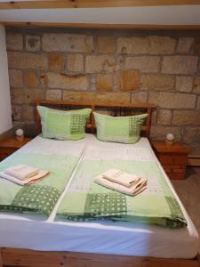 Una cama con sábanas verdes y toallas. en Ferienhaus Bildhauer Thiele, en Ottendorf