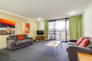 uma sala de estar com dois sofás e uma televisão em Hillcrest Apartment Hotel (formerly Central Hillcrest Apartments) em Brisbane