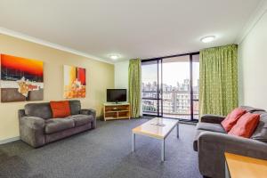 a living room with two couches and a tv at Hillcrest Apartment Hotel (formerly Central Hillcrest Apartments) in Brisbane