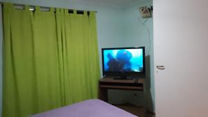 1 dormitorio con TV y cortinas verdes en Corazón Malbec en Mendoza