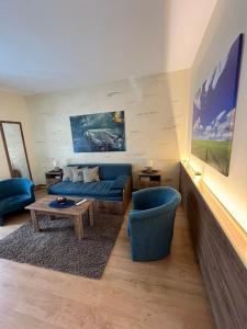 a living room with a blue couch and a table at Guest House A'storia in Ruma