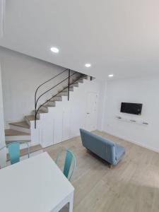 a living room with a staircase and a table and chairs at Gemini Conil in Conil de la Frontera