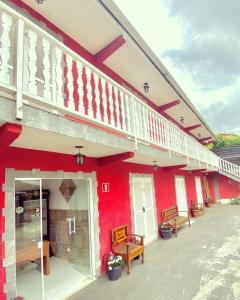 um edifício vermelho com bancos à sua frente em Pousada VHL - Campos do Jordão em Campos do Jordão