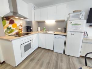a white kitchen with white cabinets and appliances at Résidence des Jardins, wifi in Luchon
