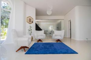 a living room with two white chairs and a blue rug at Aton Cabanas Boutique in Canela