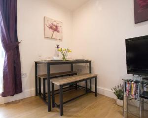 a table with a bench in a room with a tv at Cosy 1 Bedroom Apartment - Newbury High Street in Newbury