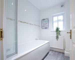 baño blanco con bañera y ventana en Cosy 1 Bedroom Apartment - Newbury High Street en Newbury
