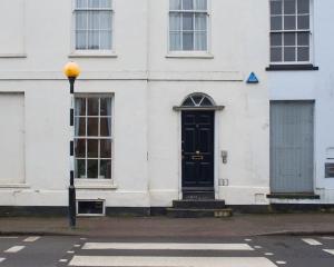 a white building with a black door on a street at Cosy 1 Bedroom Apartment - Newbury High Street in Newbury