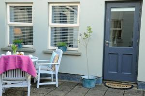 um alpendre com uma mesa e cadeiras e uma porta azul em 4 Tom's Lane em Bantry