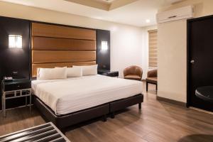 a bedroom with a large bed with a wooden headboard at Hotel Astor Tijuana in Tijuana