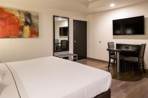 a bedroom with a bed and a table and a television at Hotel Astor Tijuana in Tijuana