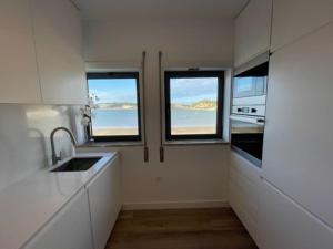 uma cozinha com três janelas e vista para o oceano em Apartamento em frente à Praia em São Martinho do Porto