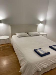 ein großes weißes Bett mit zwei Handtüchern darauf in der Unterkunft Apartamento em frente à Praia in São Martinho do Porto