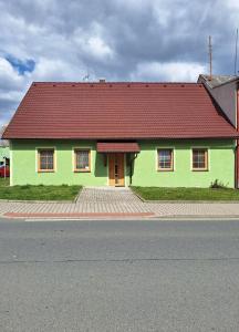 a green house with a red roof on a street at Chalupa u Šobrů 