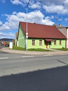 a green building with a red roof on a street at Chalupa u Šobrů 