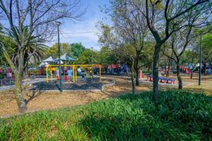 un parque con un parque infantil con equipo amarillo y árboles en Loft Lomas de Chapultepec en Ciudad de México