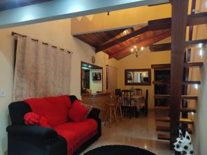 a living room with a red couch and a dining room at Chácara Recanto da Mata in Cunha