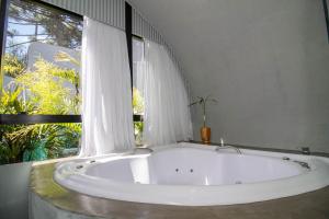 a large white bath tub in a room with a window at Aton Cabanas Boutique in Canela