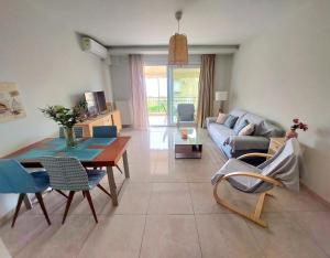 a living room with a couch and a table and chairs at Myrsini’s sea view apartment in Nea Peramos