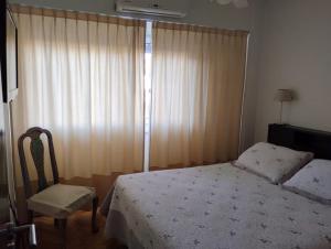 a bedroom with a bed and a chair and a window at Departamento Olivos-zona puerto in Olivos