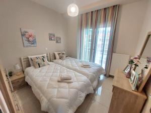 two large beds in a bedroom with a large window at Myrsini’s sea view apartment in Nea Peramos