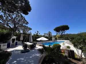 a pool with tables and umbrellas in a yard at Royal Course Villa, Vale do Lobo in Vale do Lobo