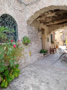 斯波萊托的住宿－Casa Borgo Marco e Cristina，石头建筑,带鲜花和植物的庭院