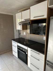 a kitchen with white cabinets and black counter tops at Silverton Private Apartment in Pretoria