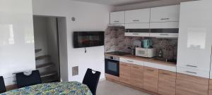 a kitchen with white cabinets and a table and chairs at Boróka Ház in Orfű