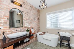 a bathroom with a white tub and a brick wall at Sweet Magnolia 1 or 2 BR Suite St Kilda Cambridge with Complimentary Continental Breakfast in Cambridge